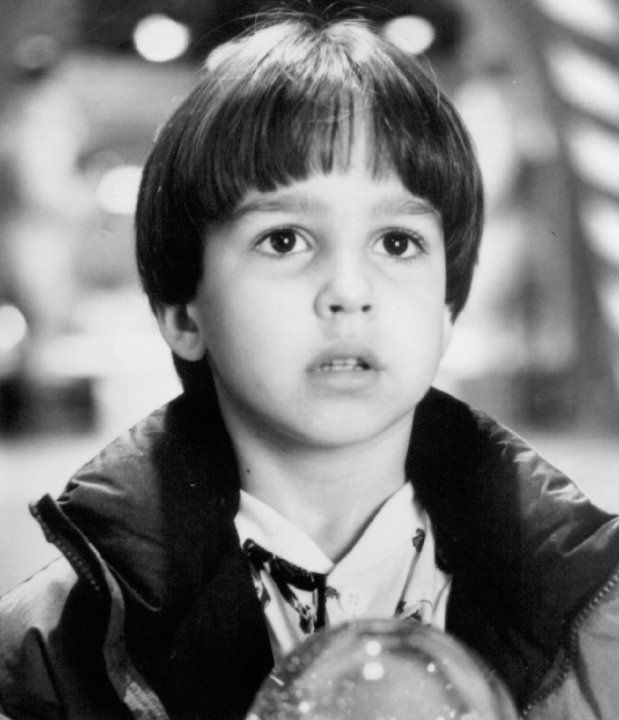 black and white photograph of a young boy holding an object in front of his face