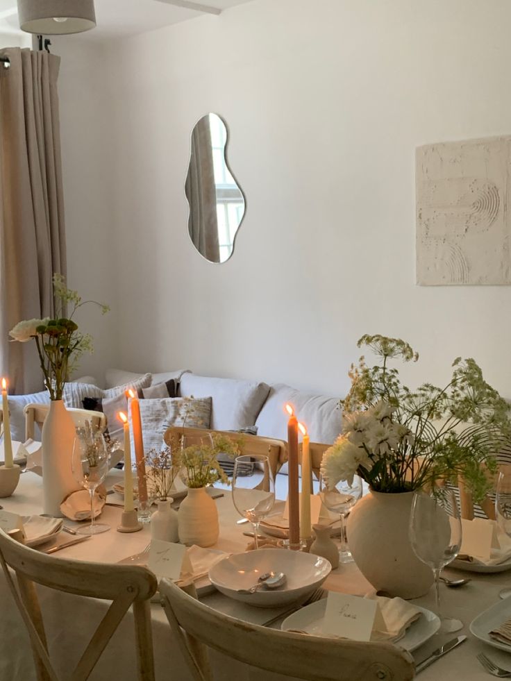 a dining room table is set with candles and plates