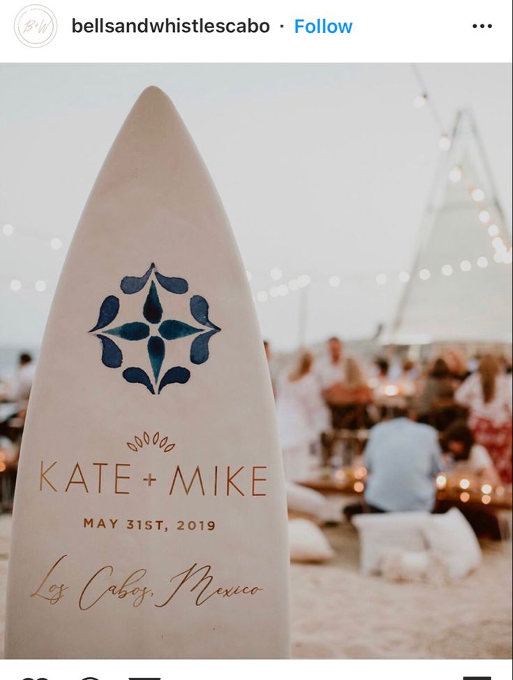 a surfboard with the name kate and mike on it sitting in front of some people