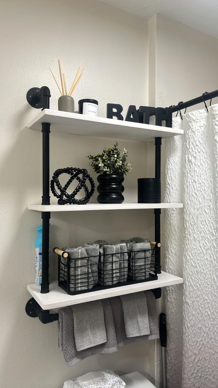 bathroom shelves with towels, toilet paper and other items on top of them in front of a shower curtain