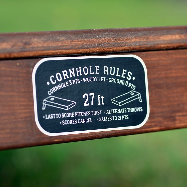 a close up of a sign on a wooden bench with grass in the back ground