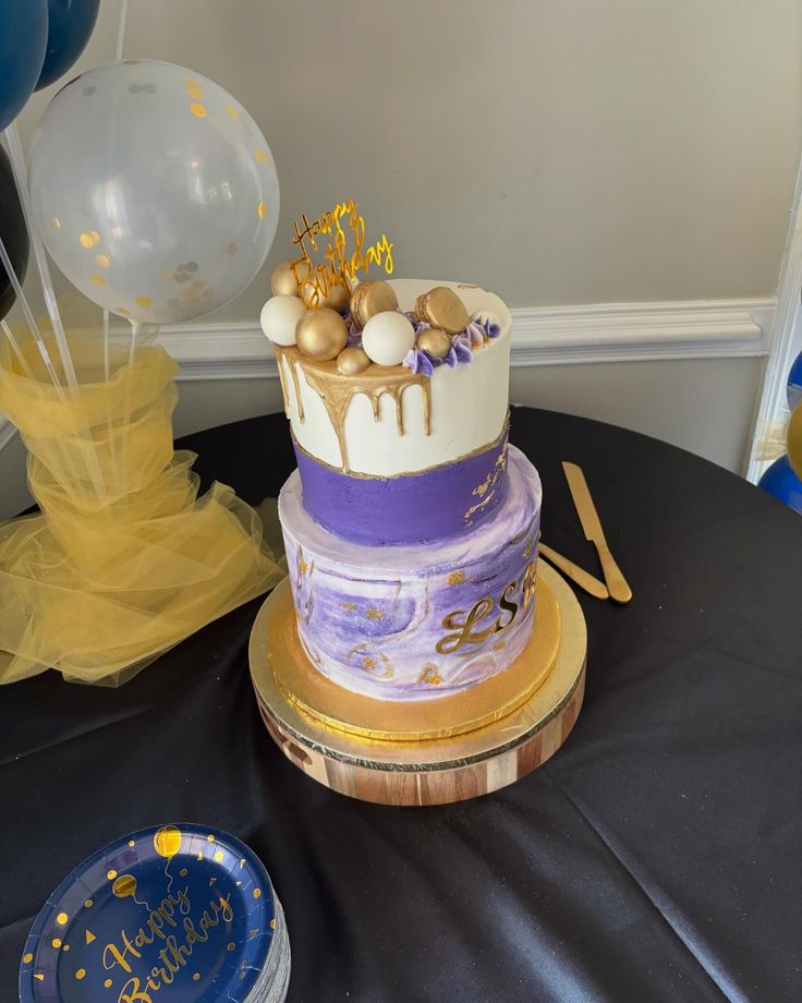 a birthday cake sitting on top of a table next to balloons and confetti