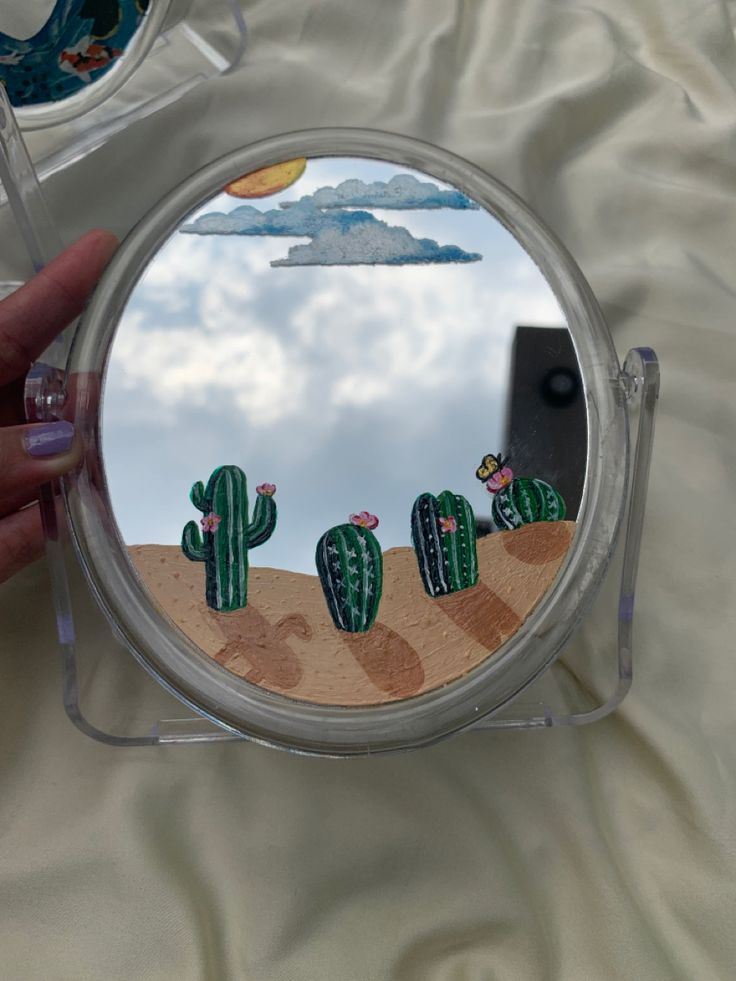 a person is holding up a small mirror with cactus designs on the front and sides