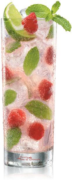 a tall glass filled with ice and raspberries on top of a white surface