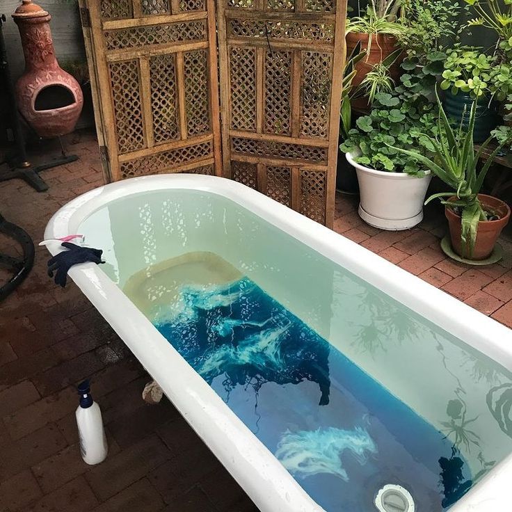 an old bathtub with blue paint on the bottom and sides in front of potted plants