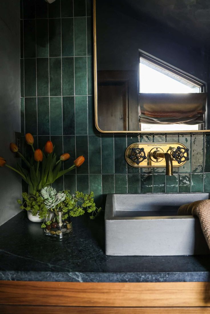 a bathroom sink sitting under a mirror next to a counter top with flowers on it