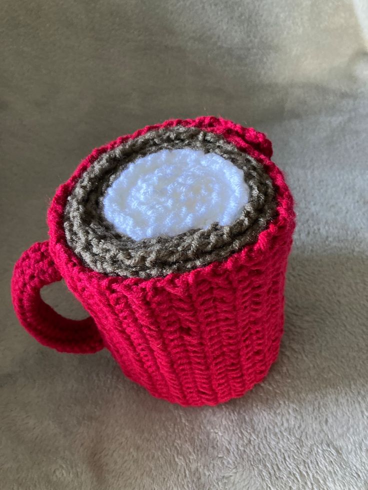 a knitted coffee cup cozying in red and grey yarn with a white center