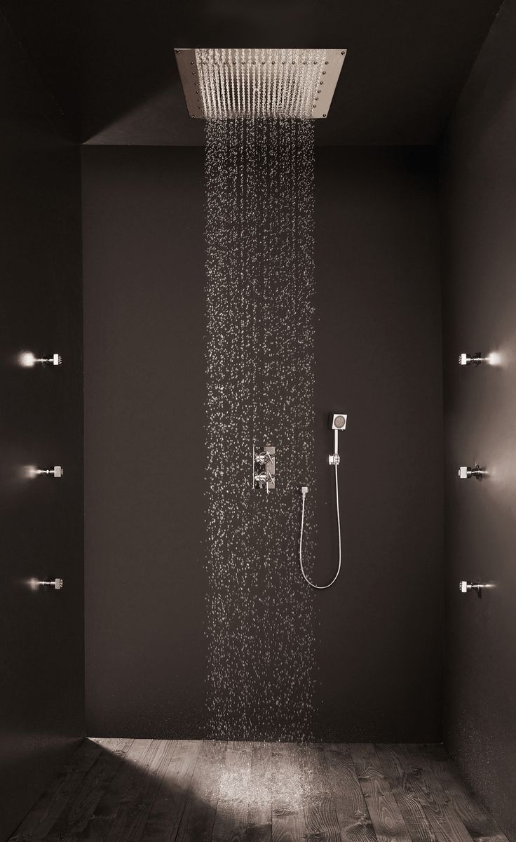 a shower head in the middle of a room with wood floors and black wall paint