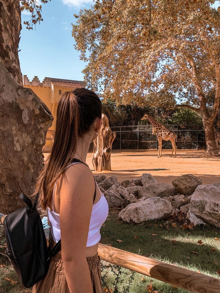 a woman standing in front of a giraffe at the zoo