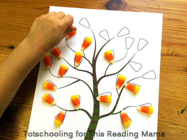 a child's hand is drawing a tree with candy