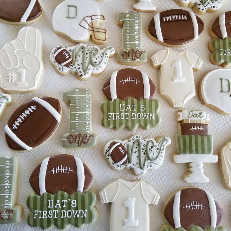 decorated cookies are arranged in the shape of footballs and baby's first names