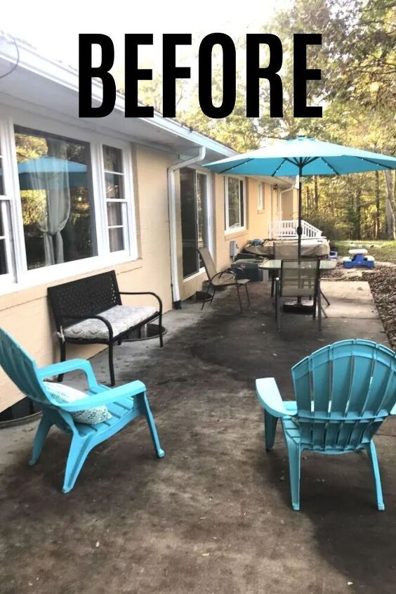 two lawn chairs sitting on top of a dirt covered ground next to a house with an umbrella