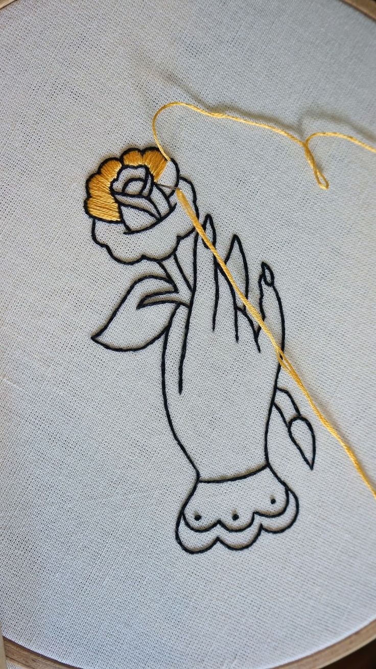 a close up of a embroidery on a white piece of cloth with a yellow thread