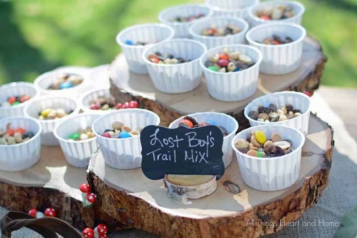 a table topped with lots of small cups filled with candy and candies next to a chalkboard sign