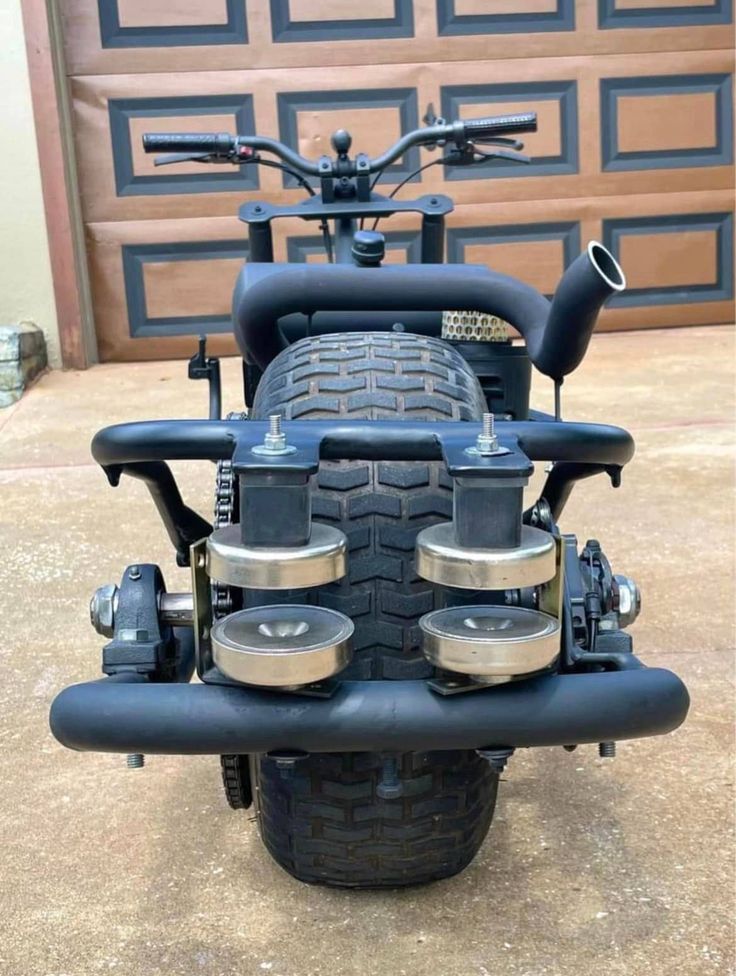 the front end of a motorcycle parked in front of a garage door with its seat up