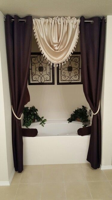 a bath tub sitting under a window next to a planter filled with potted plants