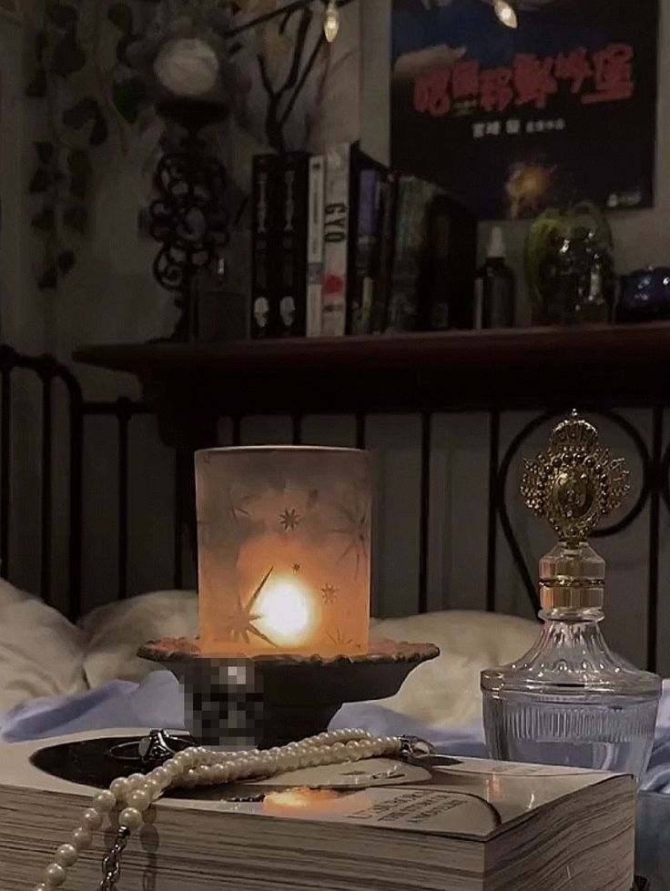 an open book on a table with a lit candle in front of it and some books