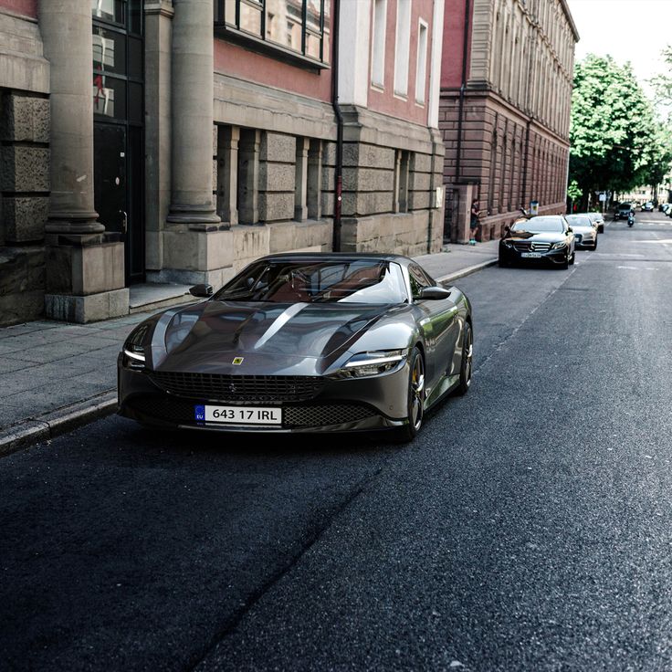 a silver sports car parked on the side of a street next to tall brick buildings