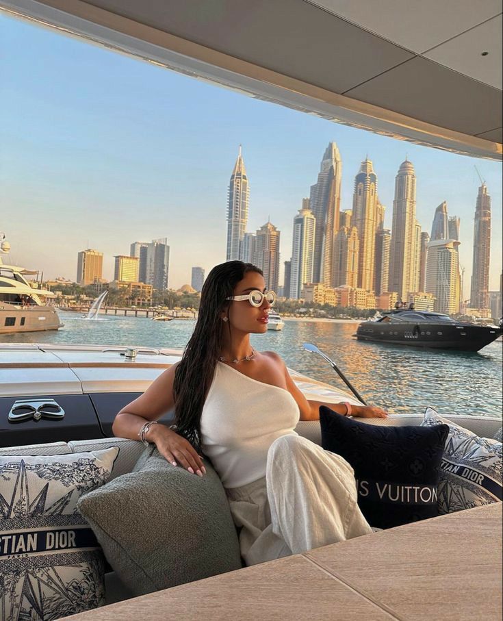 a woman sitting on the back of a boat in front of a cityscape