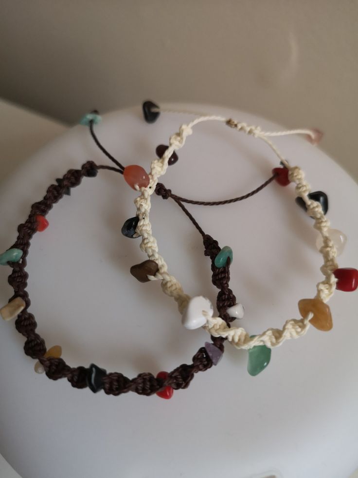 two bracelets with beads and hearts are on top of a white surface, next to each other