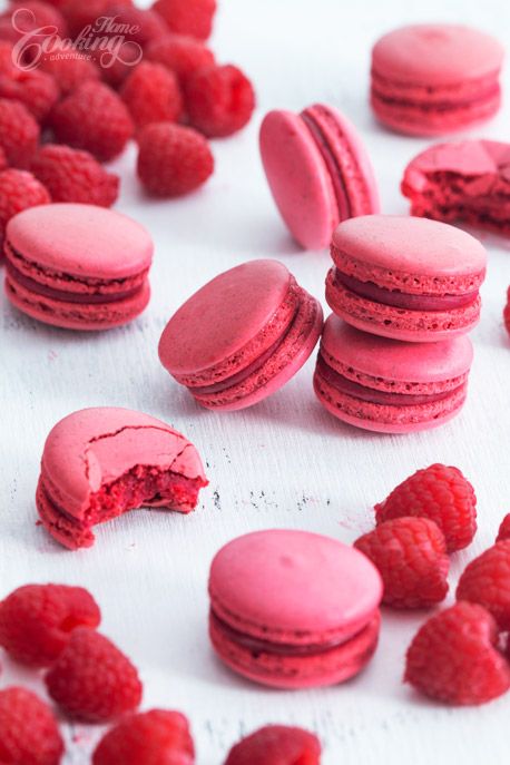 pink macaroons and raspberries on a white surface