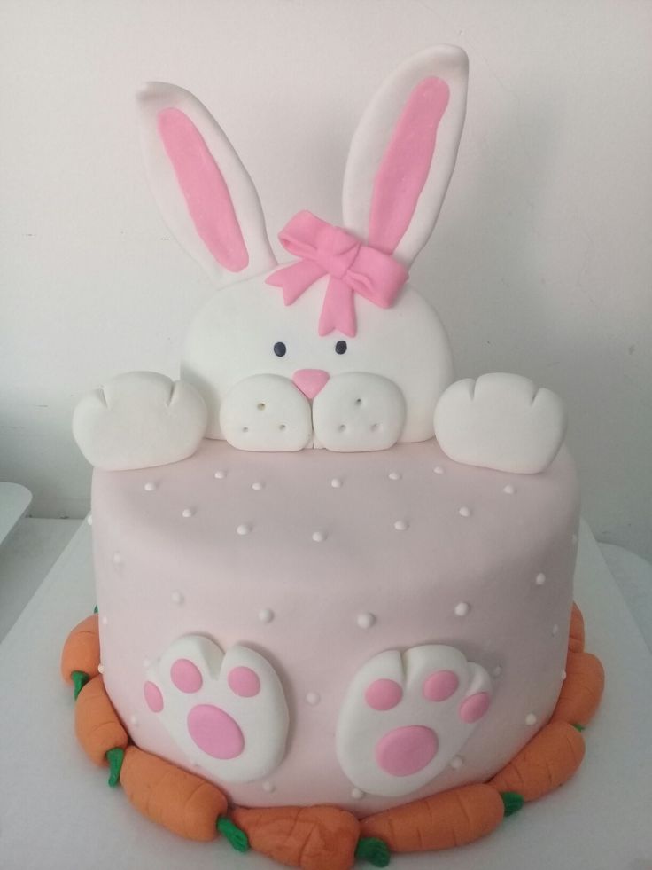 a cake decorated with white frosting and pink icing has bunny ears on it