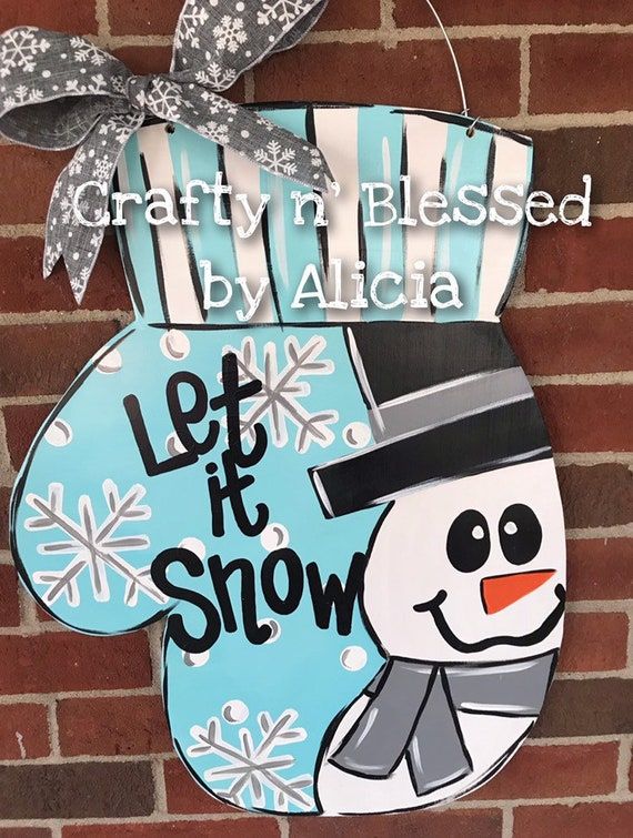 a sign that says let it snow on the side of a brick wall with a snowman