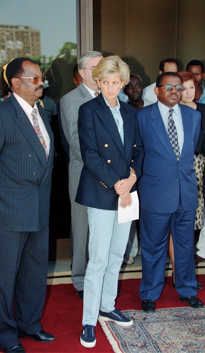 two men and one woman are standing in front of a group of people wearing suits