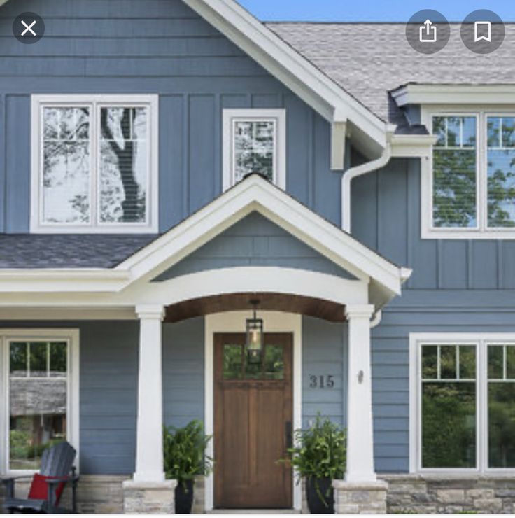 a blue house with white trim and two large windows on the front door is shown