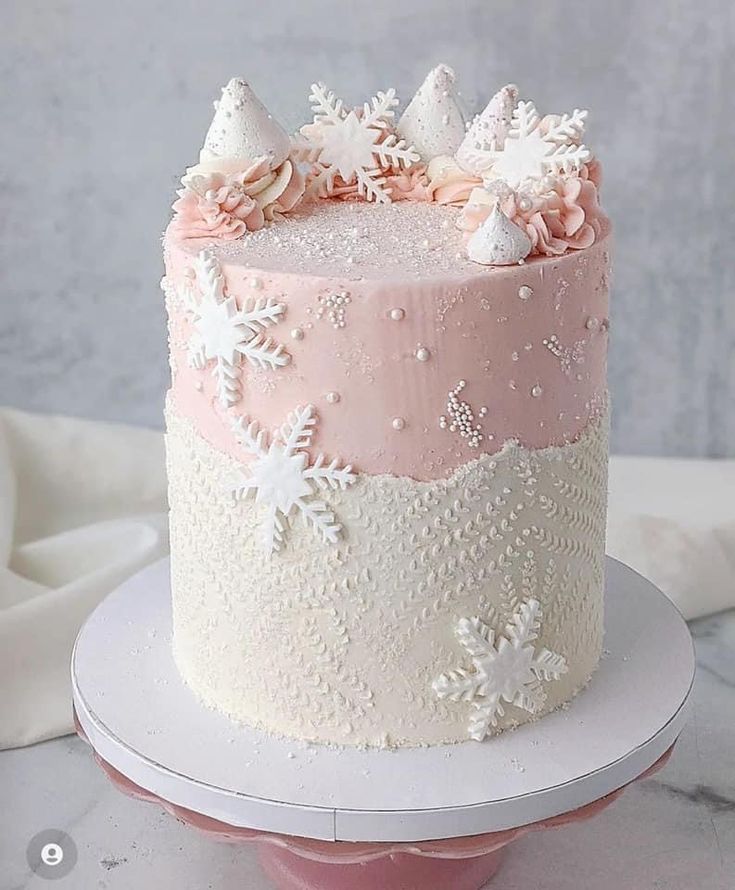 a pink and white cake with flowers on it's icing is sitting on a plate