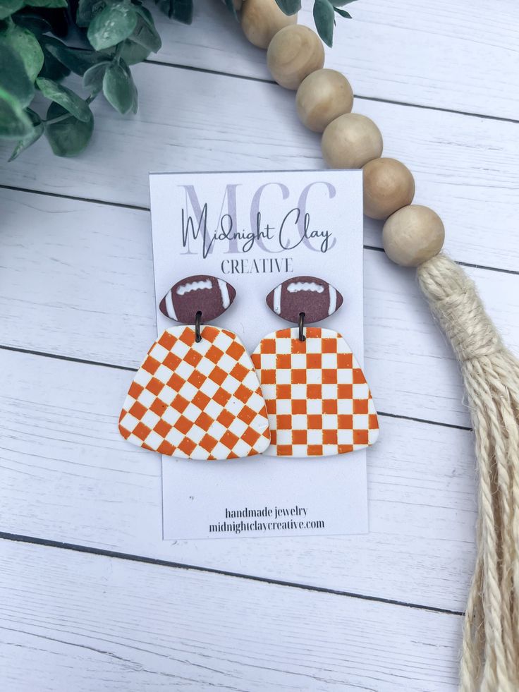 an orange and white checkered football themed earrings with a tassel hanging from it