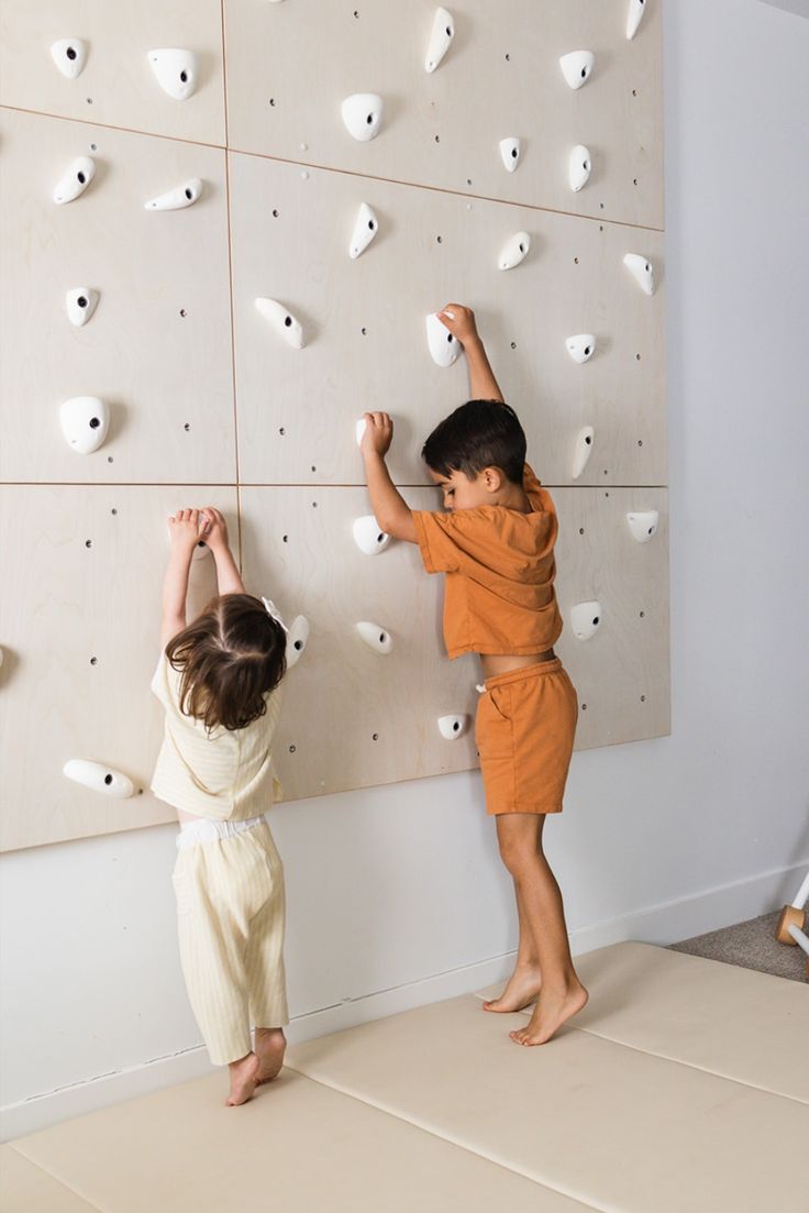 two young children climbing on a rock wall