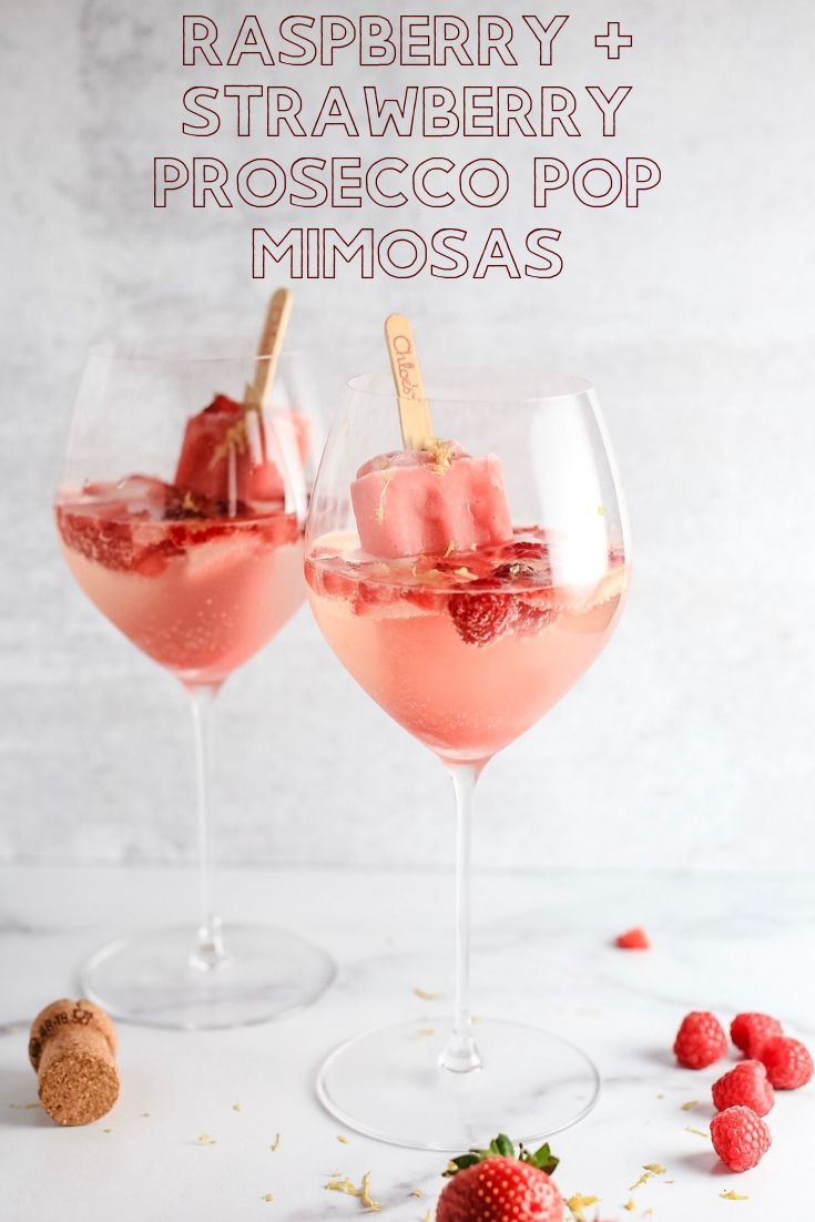 raspberry and strawberry prosecco pop mimosas in wine glasses with strawberries