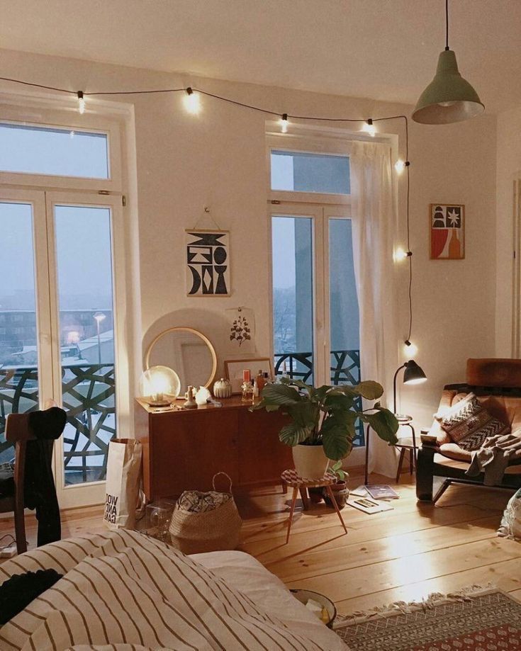 a living room filled with lots of furniture next to large window covered in string lights