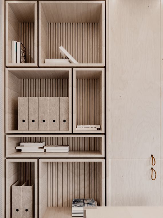 a bookshelf filled with lots of wooden boxes and binders next to a white wall