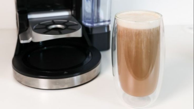 a coffee maker next to a glass filled with liquid