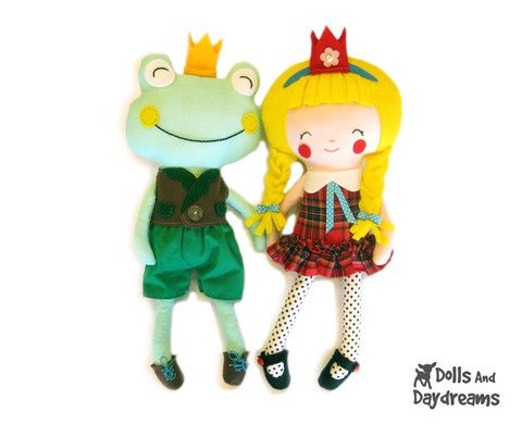 two dolls are standing next to each other on a white surface, one is wearing a green dress and the other has a red crown