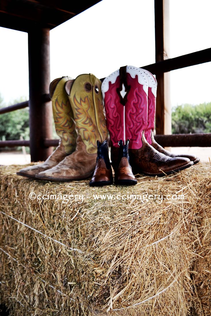 four pairs of cowboy boots sitting on top of a bale of hay next to each other