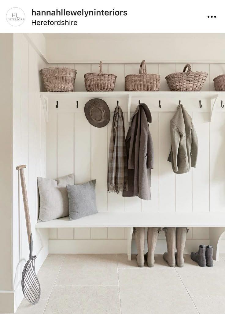 a coat rack filled with lots of coats next to a white bench and some baskets