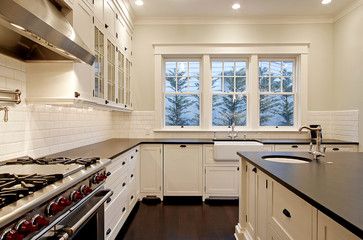 a large kitchen with white cabinets and black counter tops on the counters is pictured in this image