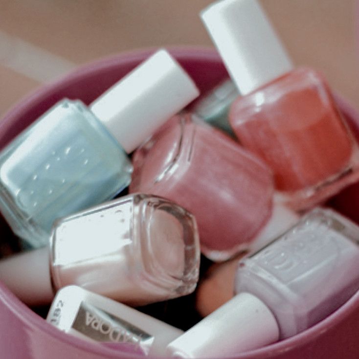 a pink cup filled with different colored nail polishes