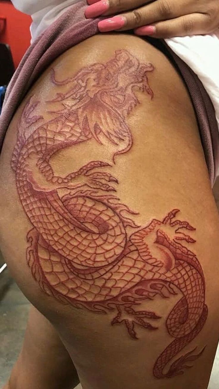 a woman with a dragon tattoo on her thigh