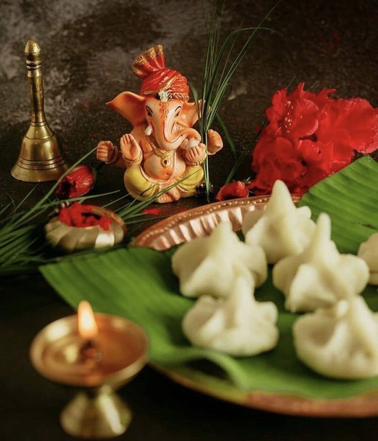 there is an elephant figurine sitting on a plate next to some flowers and candles