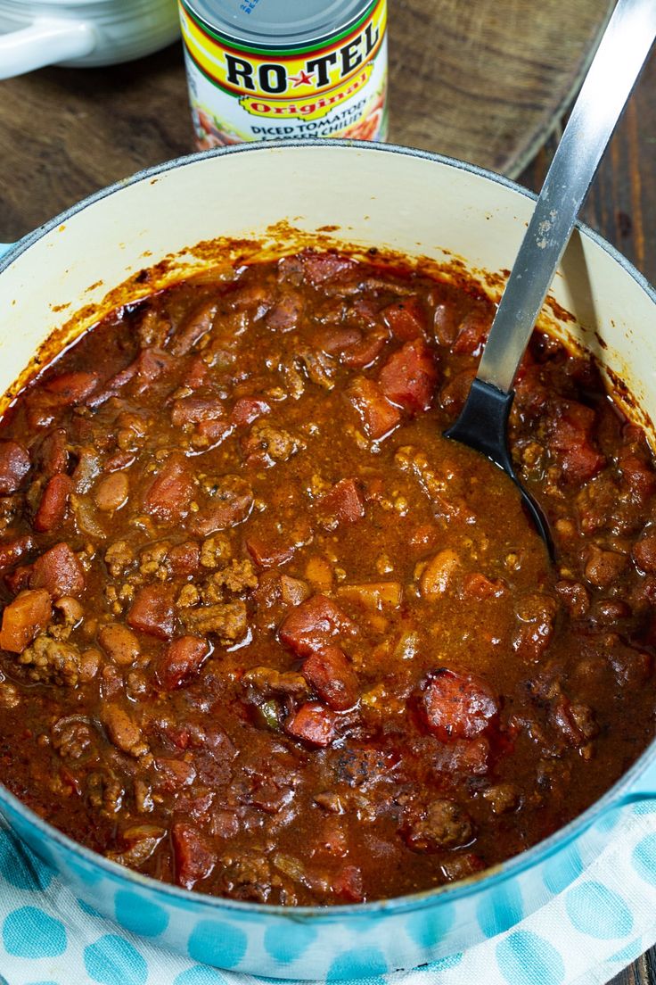 a large pot filled with chili next to a can of hot sauce