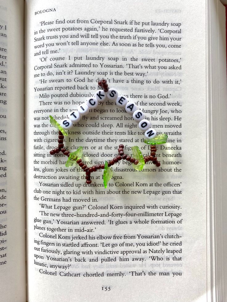 an open book with a bracelet made out of beads and leaves on it's pages