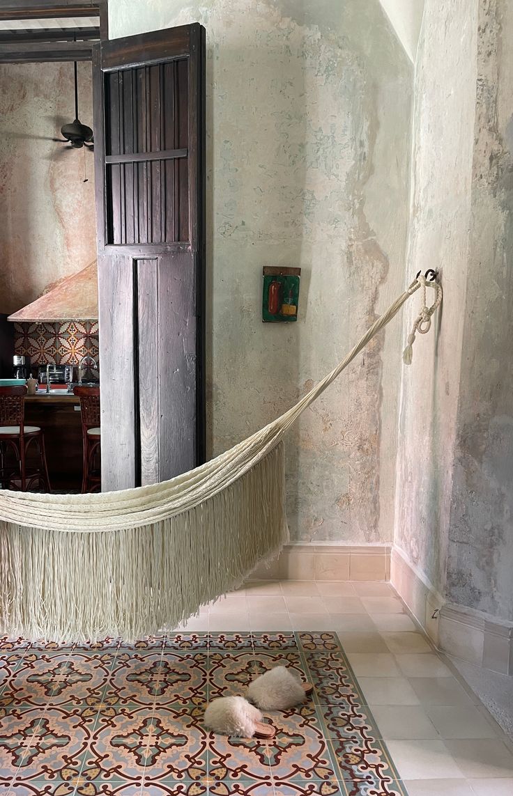 a hammock hanging from the ceiling in a room with a rug on the floor