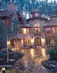 a large stone house with lots of windows and lights on it's front porch