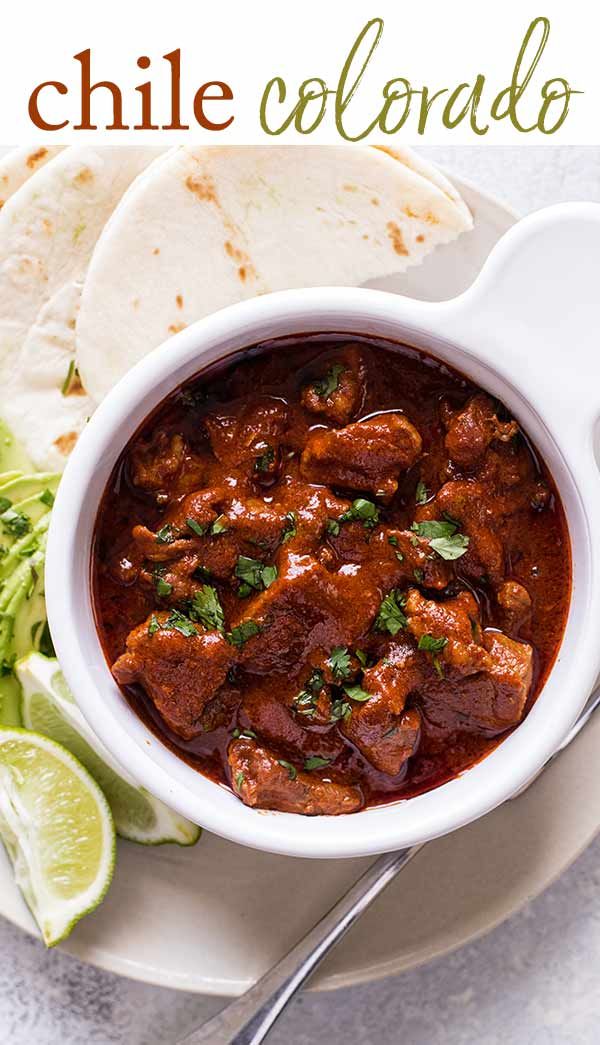 a white bowl filled with chili and meat next to tortilla chips on a plate