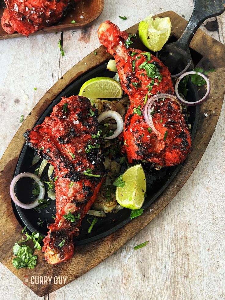 grilled fish with limes and onions on a wooden platter