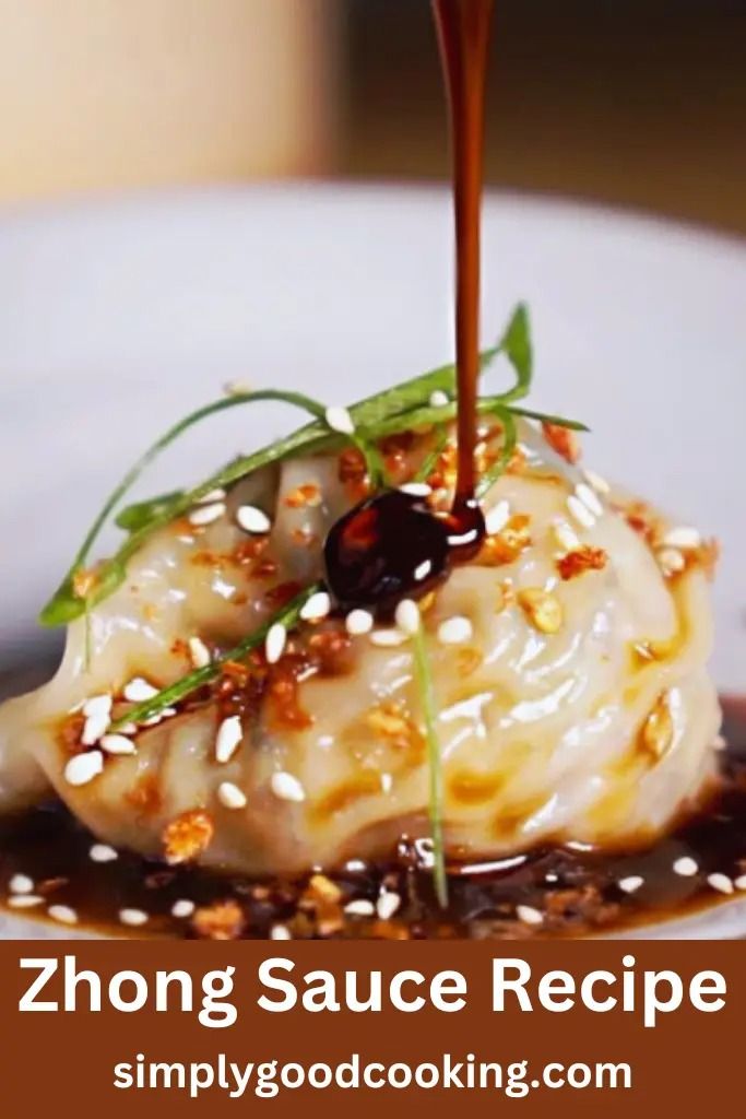 a white plate topped with dumplings covered in sauce and garnished with sesame seeds